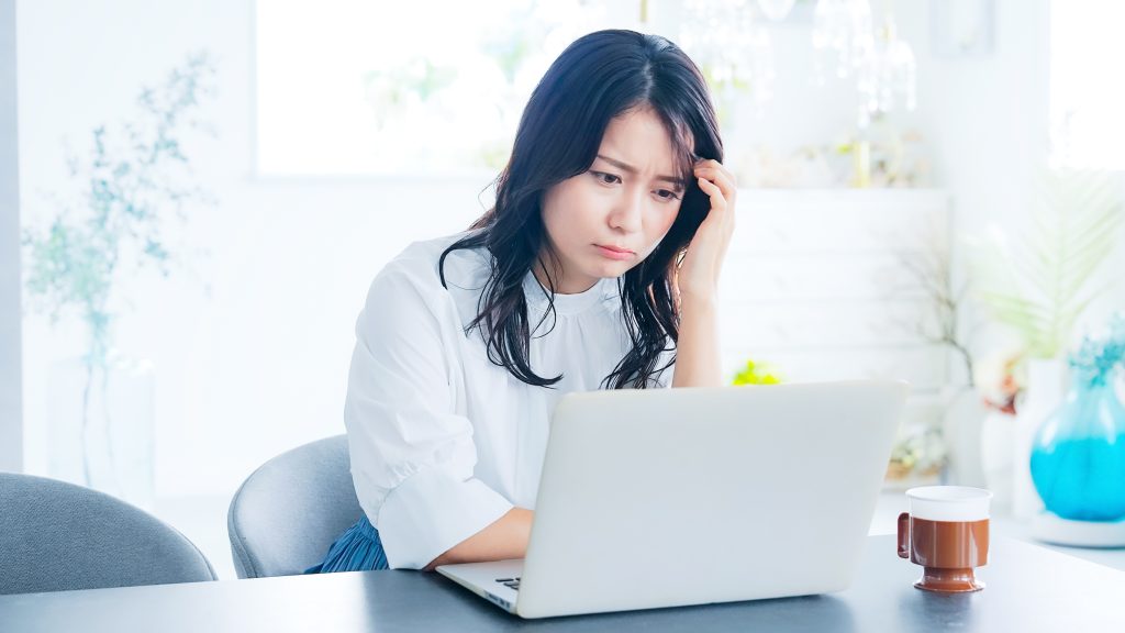 パソコンの前でイベントの来場データ整理やExcelの集計作業に頭を悩ませる女性会社員