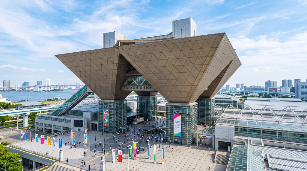 青空を背景にした、東京ビッグサイトの逆ピラミッド型会議棟と広場の俯瞰写真。